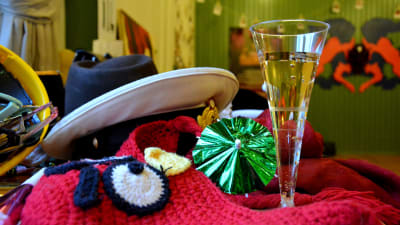 ett glas med bubblig dryck och en massa huvudbonader på varandra i olika färger och ett litet glassparaply i grönt