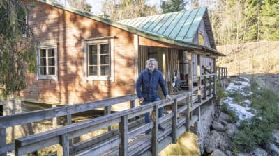 En man står på uteveranda, en slags bro vid en gammal byggnad.