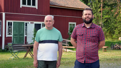 Museiguide Jarmo Kujala och museichef John Björkman framför ett rött hus på Sagalunds museum.