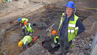 Juuso Koskinen i förgrunden, grävande arkeologer i bakgrunden.
