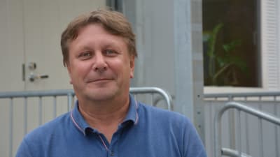 Mansperson i blå t-skjorta ser in i kameran. 