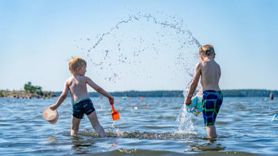 Barn leker i vattnet vid en badstrand i Nordsjö i Helsingfors den 25 juni 2020.