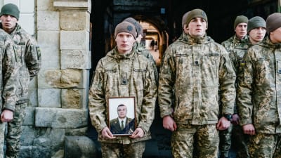 Ukrainalainen sotilas pitää kädessään kuvaa Javorivin ilmaiskussa menehtyneestä sotilaasta.