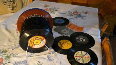 Vinylsinglar, så kallade 45-varvare, ligger på ett bord med fin duk.