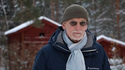 En äldre man med glasögon. Han är klädd i vinterkläder.