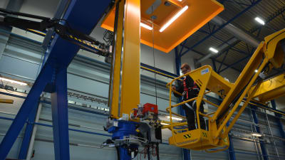 En person jobbar med hjälp av en skylift i en fabrik. 