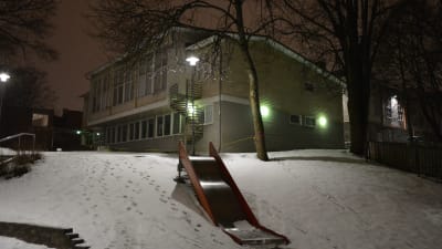 Kärnhuset vid Sirkkala skola, en gul tvåvåningsbyggnad en snöig vinterkväll.
