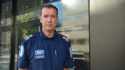 Polisen Stephan Sundqvist står framför en mörk vägg och ser in i kameran.