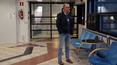 Man med glasögon och svart kavaj står och tittar ut genom fönstret i Wasalines terminal.