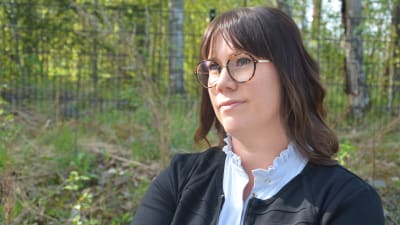 Kvinna i 35-40-årsåldern, axellångt brunt hår och glasögon. 