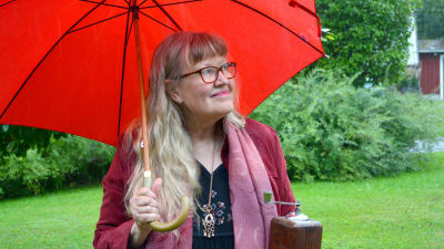 Ann-Sophie under ett rött paraply i regnet 