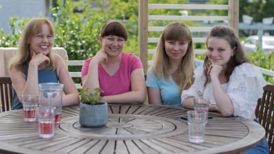 Minna Levälahti och de tre ukrainska kvinnorna som bor hos henne sitter runt ett bord på en terass.
