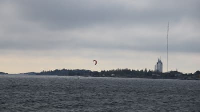 Udde med torn och mast, i förgrunden en kitesurfare.