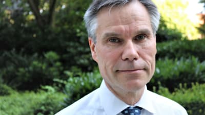 Finlands Natoambassadör Klaus Korhonen fotograferad i närbild. I bakgrunden en lummig trädgård. 