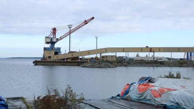 En kran vid en kaj i Kristinestad. Framför kranen går en transportlinje.