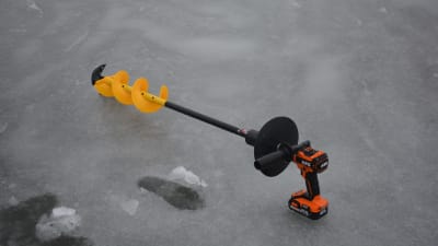En elektrisk isborr med gult bett ligger på isen vid en vak.