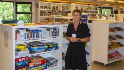 En kvinna som står framför en bokhylla. 