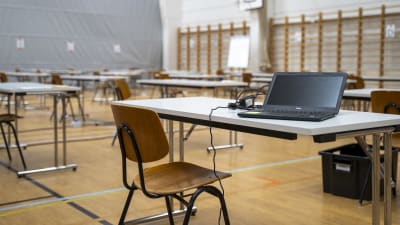En stol vid ett bord där det finns en bärbar dator under studentskrivningar.