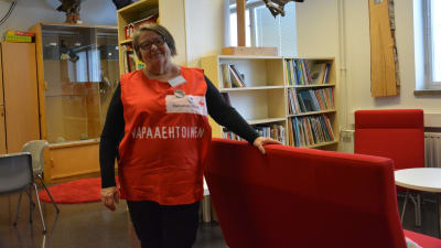 Kvinna i röd röda-korset väst i ett skolbibliotek