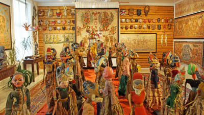 konstutställning med ett rum fyllt av tavlor och dockor och masker