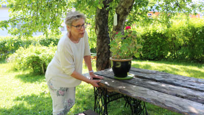 Margareta "Teta" Reinlund inspekterar ett bastant trädgårdsbord