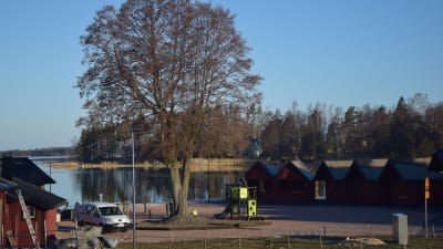 EN skärgårdshamn med strandbodar i rött. Morgon i april. Soligt