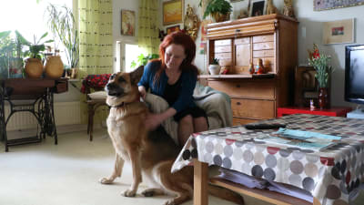Lena Bengtson sitter i sitt vardagsrum med schäferhunden Alice bredvid sig.