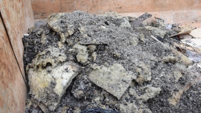 Mineralull (isoleringsmaterial) och sot i en sopcontainer.