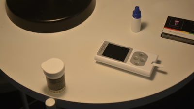 En elektronisk blodsockermätare som ligger på ett nattduksbord.