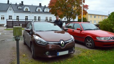 En brun och en röd bil står parkerade på en innergård.