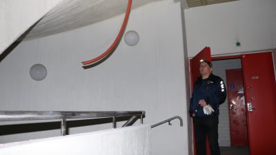 En man med lampa i pannan tittar på en röd ledning som hänger från taket.