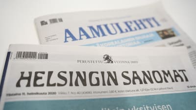 Printversionerna av tidningarna Helsingin Sanomat och Aamulehti på varandra på en vit yta.