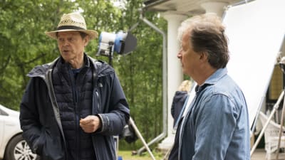 två äldre män som står på en filminspelningsplats.