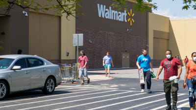 Människor med ansiktsskydd promenerar bort från en Walmart-butik