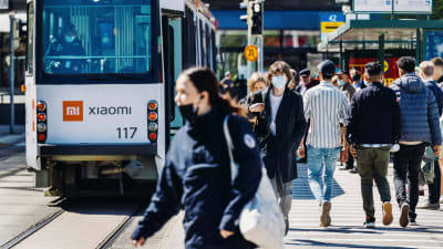 Personer med munskydd i Helsingfors centrum. Bilden är tagen i maj 2021.