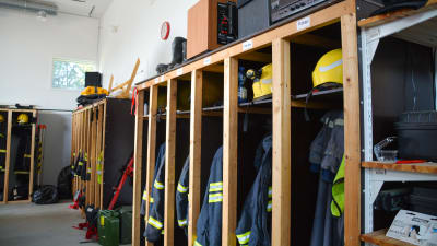 Brandmansutstyrsel hänger på rad i knaggar. 
