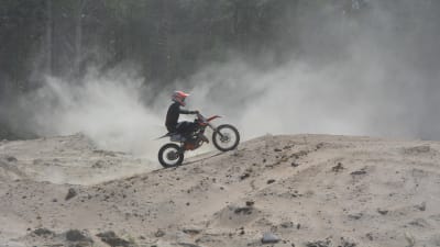 En motocrossförare åker på sand.