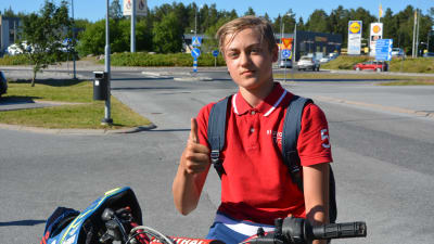En 16-årig pojke sitter på en moped och visar tummen upp.