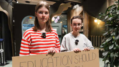 Två gymnasieelever håller i ett plakat.