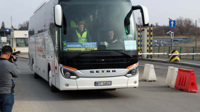 En buss med en skylt på polsk aoch ukrainska som säger att den transporterar kvinnor och barn till Warszawa.