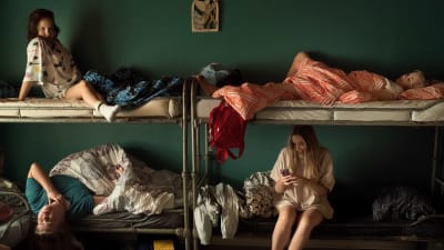 En sovsal där en fyra unga kvinnor sitter och ligger i sina sängar. Stillbild från filmen Eden. 