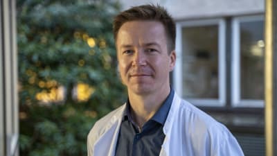 Chefsläkaren Fredrik Forsström står i vit läkarrock och tittar in i kameran.