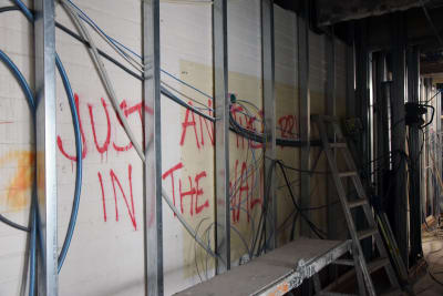 Graffiti syns på en tegelvägg som håller på och byggs om.
