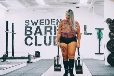 Sara Dahlström bär på två tunga vikter i ett gym. 