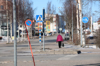 En kvinna med rosa jacka går på en gata i Närpes centrum.