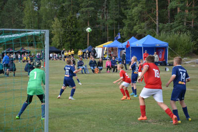 Målvakten Alexander Källund i grön skjorta och anfallaren William Wikström i röd skjorta försöker nå ett inlägg i straffområdet under en fotbollsmatch.