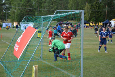 Målvakten Alexander Källund i grön skjorta räddar en boll i straffområdet framför anfallaren William Wikström i röd skjorta under en fotbollsmatch.