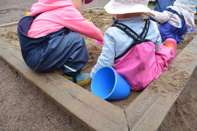 Några barn leker i en sandlåda.
