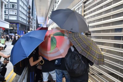 Ungdomar såg med sina paraplyer till att det var omöjligt att identifiera personen som målade graffiti på Bank of China.