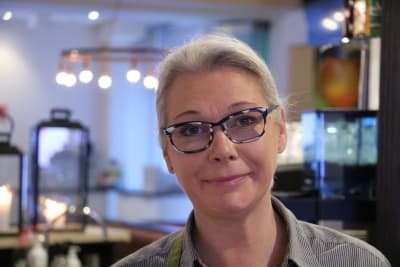 En kvinna med glasögon står bakom disken på en restaurang.
